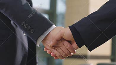 Close-up of businessmen shaking hand & greeting in office