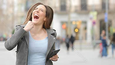 Excited woman celebrating success checks phone