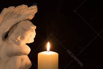 Angel and candle on dark background