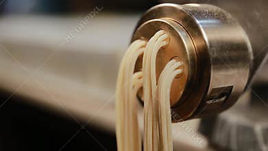 Cook preparing Italian spaghetti fettuccine with a pasta maker. Pulling long handmade macaroni in the kitchen of a restaurant to p