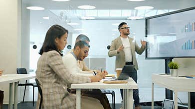 Group of people listening to boss during meeting, man is using digital screen for presentation