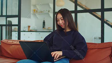 Charming asian woman working on laptop at home