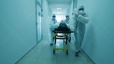 Hospital hallway with a group of doctors relocating a patient. Coronavirus hospital, COVID-19 clinic concept.