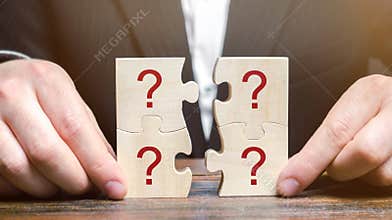 Businessman collects puzzles with question marks. Asking questions, searching for truth. Riddle mystery, investigation and