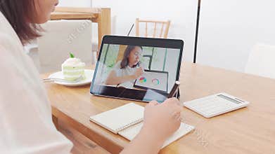 Asian woman aged 30-35 years using tablet, watching lesson online course communicate by conference video call from home, e-learnin
