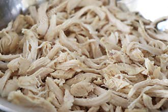 Cooked chicken that is shredded in a container.