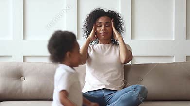 Stressed upset african mom feeling headache tired of active kids