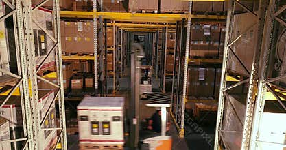 The forklift carries boxes with products at the warehouse, forklifts traveling between the rows in the warehouse
