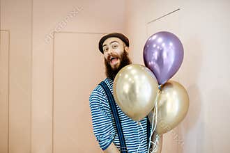Festive man with balloons indoors