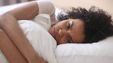 Depressed upset african woman feeling sad lying in bed alone
