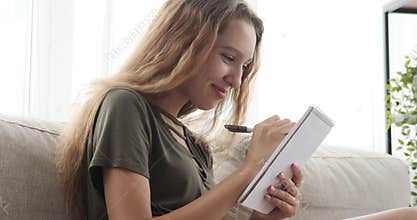 Teenage girl making shopping list in notepad