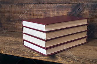 Four red books stacked on a wooden shelf