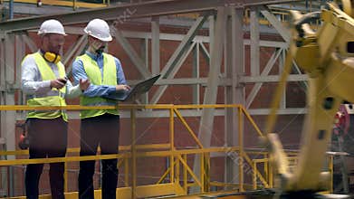 Professional factory workers at factory facility. Male workers check plant machines while walking in a facility.