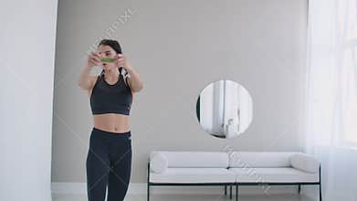 Brunette woman does warm-up and exercises in her apartment in the morning, turns the body blindly and right with arms