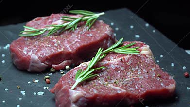 Raw steak with seasonings on a dark background