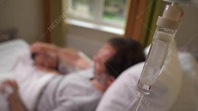 Sick man stroking sleeping wife on head in hospital