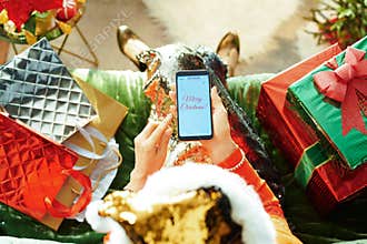 Trendy woman writing Merry Christmas email on smartphone