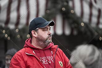 Man with beard in red hoody and black cap walking in old town 10-12-2019 Riga Latvia