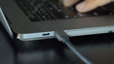 4k video of Man`s hand plugging in Cable adapter a black wire 3.2 USB Type C cable into the USB-C port is installed in the grey