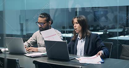Multinational Entrepreneurial Couple Engaged with Papers at Office Table