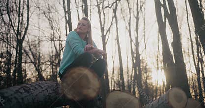 Female explorer crouching on logs in forest