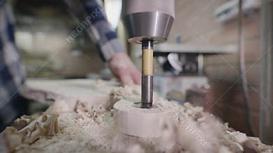 Drilling machine in a carpentry workshop. Hole in a piece of wood.