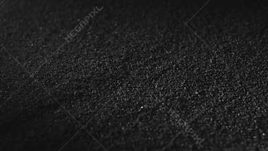 Carbon powder or black charcoal powder. Dark textured background. Volcano dust moving on surface, close-up