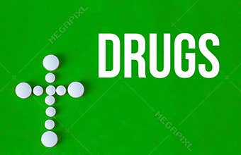 White pills making a cross green background
