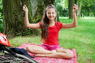 Girl relaxing in yoga pose in a park