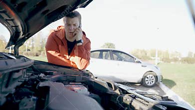 Upset man using his phone to call for roadside assistance after a breakdown