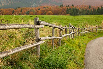 Wooden fence borders a mountain pasture, rural path