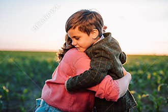 Loving smiling son hugs mom tightly. Tender family scene. Cute 3 year old ukrainian kid with mother. Parenthood