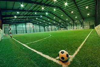 Soccer ball on green grass in an indoor playground