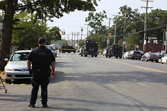 NYPD Strategic Response Group Officer at road blockade with swat and bomb squad vehicles responding to armed gunman