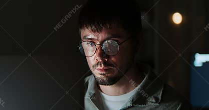 White Caucasian male software developer work late night, program coding in home office