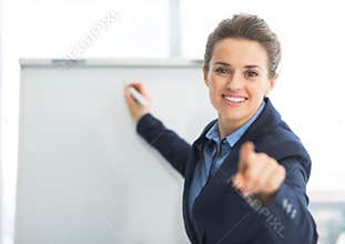 Business woman near flipchart pointing in camera