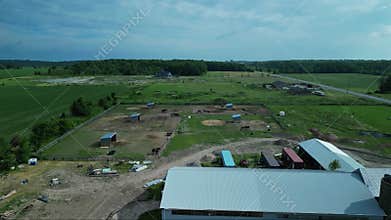 A rural horse property with stables, a silo, and fenced paddocks in the early morning