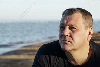 Handsome middle-aged man thinking at the beach