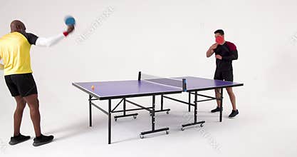 Playing table tennis, two men competing in match in studio setting