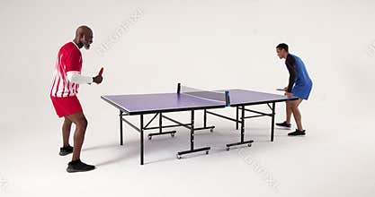 Playing table tennis, two men competing intensely in studio setting