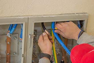 Electrician connecting wires in the electrical cabinet