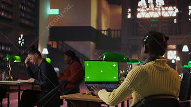 Preteen scholar works on a school assignment with green screen in the library