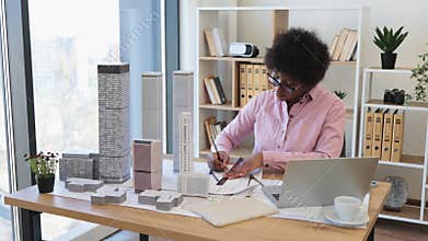 African woman architect working on city model in office