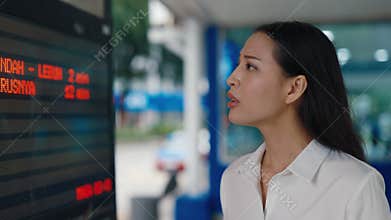Asian Business Girl Stands By The Arrival Information Board Standing in the Station.