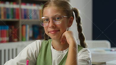 Schoolgirl studying at school desk portrait girl child Caucasian kid daughter pupil student learner looking at camera