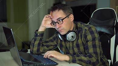 An attentive student in a plaid shirt studies science at home. man holding laptop and looking extremely perplexed on