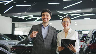 Happy customers celebrate new car purchase at a modern dealership during daylight hours