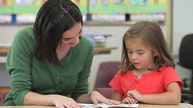 Teacher Reading Book With Female Pupil