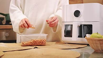 Woman preparing chickpeas in air fryer in kitchen