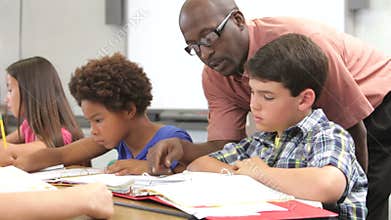 Teacher Helping Male Pupil In Class